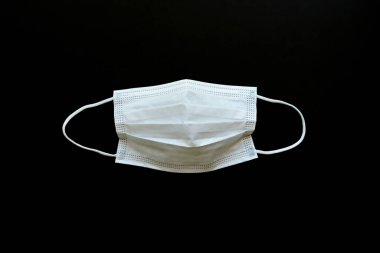 Tıbbi yüz maskesi siyah arkaplanda izole edilmiş.