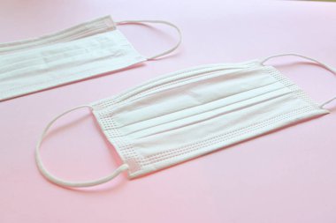 Pembe arka planda tıbbi yüz maskesi.