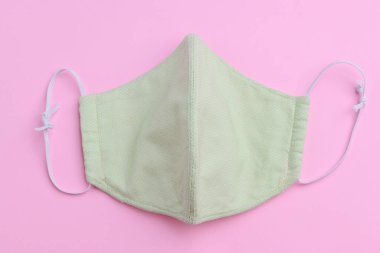 Yeşil yüz maskesi tasarımı. Moda kumaşından el yapımı. Pembe arka planda pamuk kumaş.