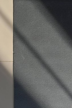 Yoga minderi yan fitness salonunda yere konur. İmaj sporu arka planı sabah güneş ışığıyla çalışır.