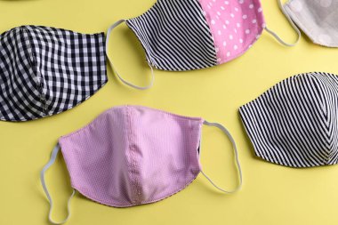 Renkli moda maskesinin düz dizaynı sarı arkaplanda kumaştan yapılmış el yapımı.