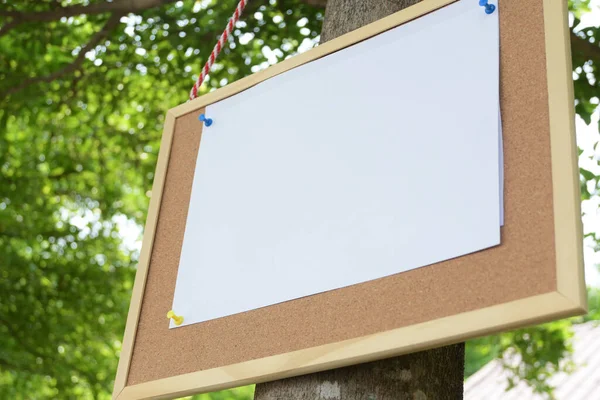 white paper post blank text message note on notice board hanging on tree in garden