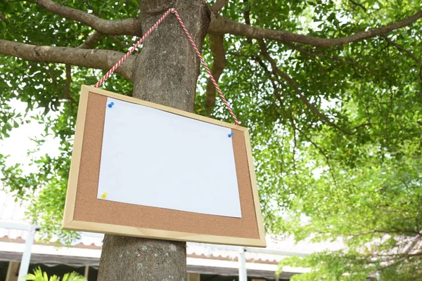 white paper post blank text message note on notice board hanging on tree in garden