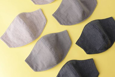 Moda yüz maskesinin düz dizaynı sarı arkaplanda kumaştan yapılmış el yapımı.