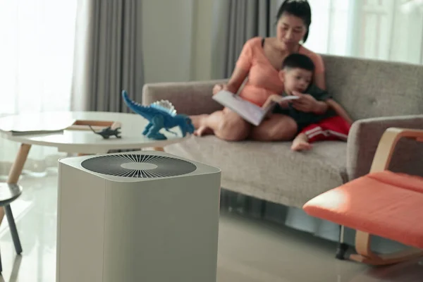母親と子供が家の中で読書する部屋の空気清浄機 — ストック写真