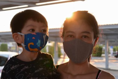 Asyalı sevimli çocuk ve kadın anne açık havada sabahleyin maske takıyor kendinizi hava kirliliği ve salgın hastalıklardan koruyun.