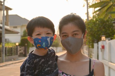 Asyalı sevimli çocuk ve kadın anne açık havada sabahleyin maske takıyor kendinizi hava kirliliği ve salgın hastalıklardan koruyun.