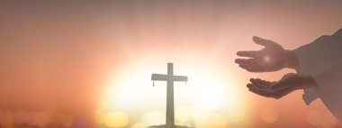 Good Friday concept: Silhouette Jesus Christ hands showing scars over cross sunset background. clipart