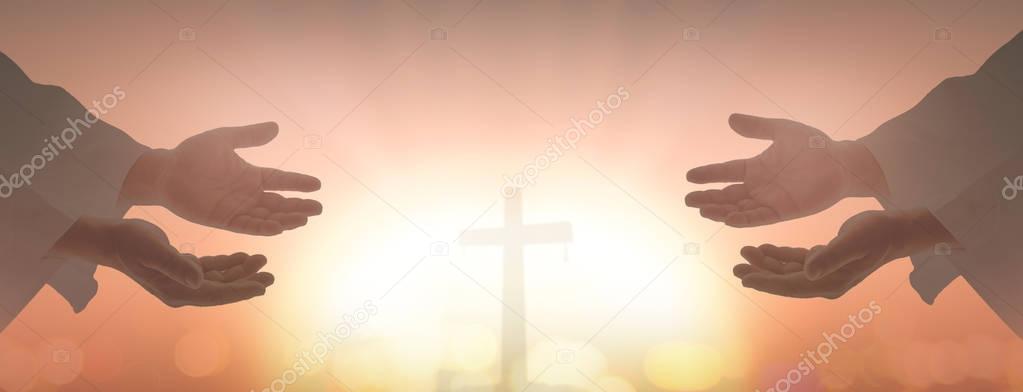 Good Friday concept: Silhouette two human open two empty hands with palms up over blurred cross sunset background.