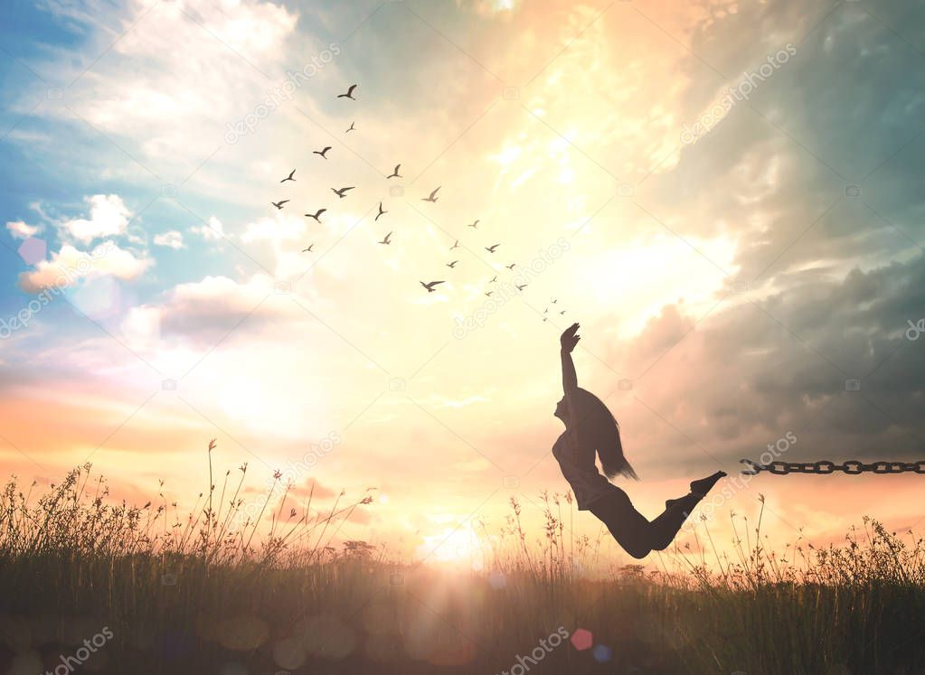 World mental health day concept: Silhouette of a girl jumping at autumn sunset meadow with her hands raised