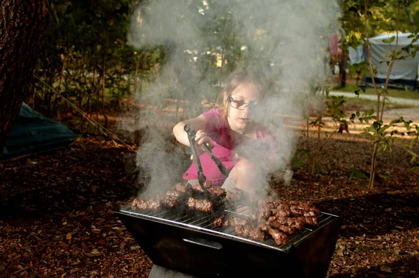 Menina caucasiana cozinhar o cevapi, um prato grelhado de carne picada, um tipo de salsicha sem pele, em churrasqueira ao ar livre . — Fotografia de Stock