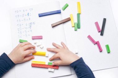 Beyaz arka plan üzerinde renkli plastik numara çubuklarla açık alıştırma kitabı.