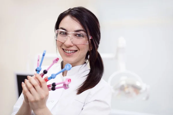 Jovem dentista feminina segurando equipamentos — Fotografia de Stock