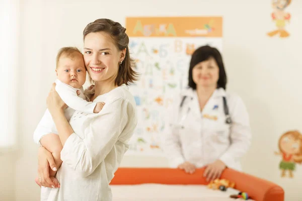 Bir bebek tutan genç gülümseyen kadın