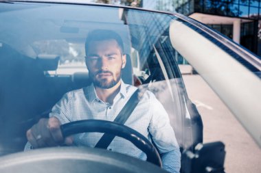 Ofisin yakınındaki arabada ciddi görünümlü genç bir adam.