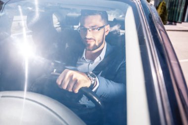 Gülümseyen genç adam araba kullanıyor. Özgüven kavramı.