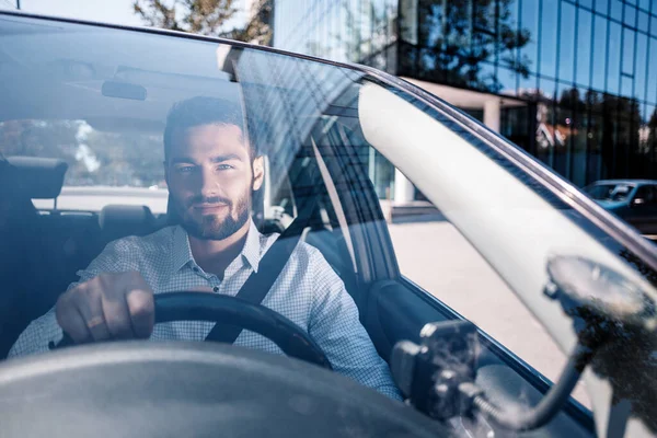 笑顔若い男身に着けていますChekeredシャツで車 ロイヤリティフリーのストック写真