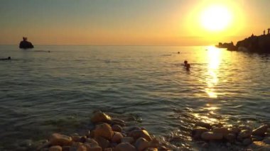İnsanlar günbatımı zaman denizde yüzmek