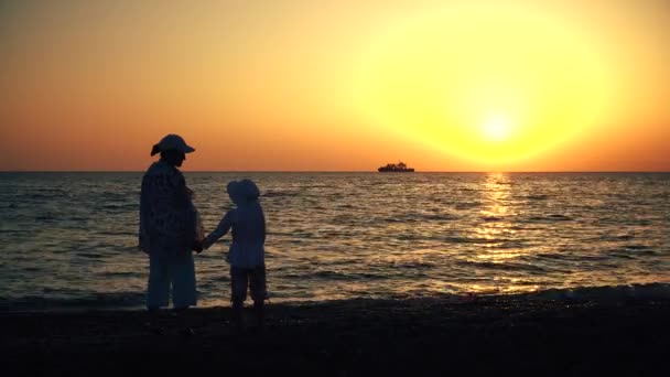 Moeder en kind silhouetten en zonsondergang boven de zee — Stockvideo