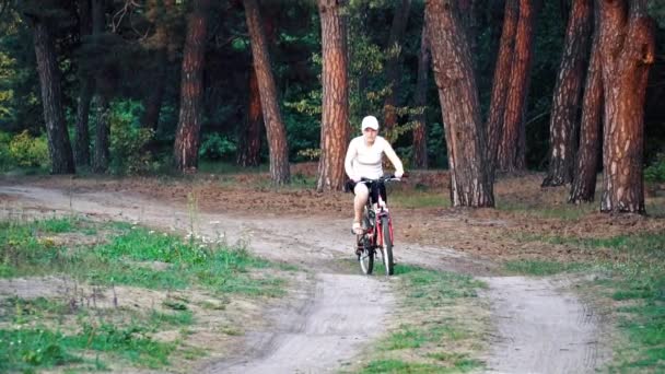 Mulher está montando uma bicicleta através da floresta — Vídeo de Stock