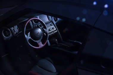 Dış Nissan GT-R, koyu renk akort garajında kırmızı ve gri deri direksiyonlu.