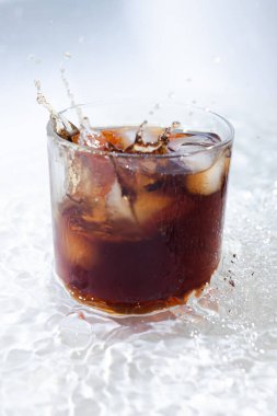 Kola ve buzlu viski kokteyli şeffaf bir bardakta güzel su damlalarıyla.