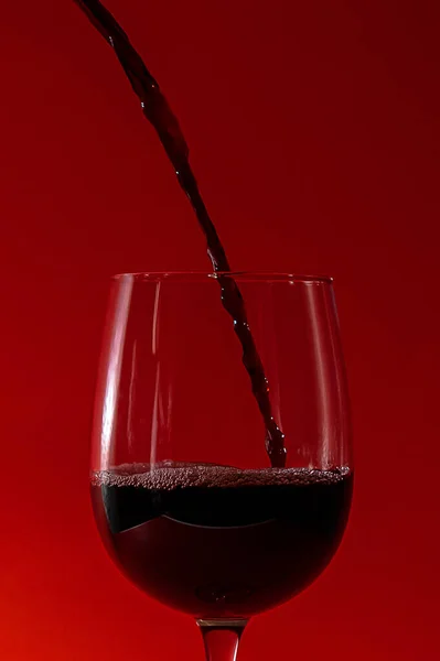 Pouring Red Wine Glass Wine Glass Long Leg Red Background — Stock Photo, Image