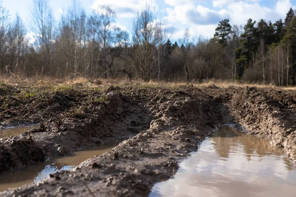 broken dirt road with deep puddles and pits