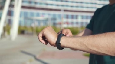 Koşarken akıllı saat kullanan genç sporcunun elleri, yakın plan.