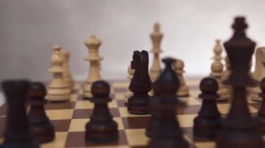 Satranç taşlarını tahtaya yakın tut. Yakın plan. Satranç tahtası ve figürler. Kameranın dairesel hareketi, doli çekim.