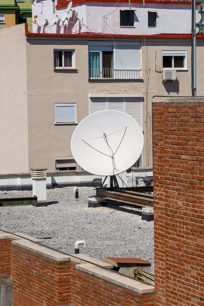 Satellite dish on the gravel roof of a building.