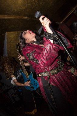 Malaga, İspanya - 09 Mayıs 2015: Kırmızı elbiseli genç bayan rock vokalisti, uzun saçlı sarışın bir adamla birlikte mavi bas gitar çalıyor. Özür dilerim, heavy metal grubu konser veriyor. Balık bakışı.