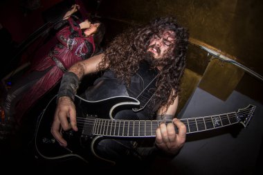 Malaga, İspanya - 09 Mayıs 2015: Sakallı, uzun saçlı, gitar çalan adam, bayan bir rockçı vokalistin yanında. Özür dilerim, heavy metal grubu konser veriyor. Balık bakışı.