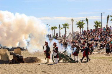 Malaga, İspanya - 26 Ekim 2014: 18. yüzyıl Fransız askerleri top ateşliyor. Barut dumanı. Arkalarında kalabalık olan oyuncular. Napolyon Corsair üssünün tarihsel canlandırması.