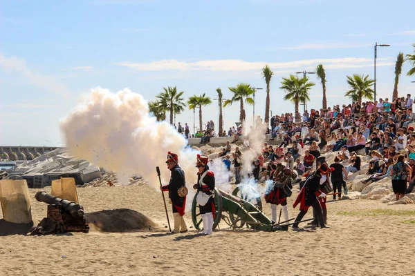 Malaga, İspanya - 26 Ekim 2014: 18. yüzyıl Fransız askerleri barutla top ateşliyor. Arkalarında kalabalık olan kadın ve erkekleri canlandırıyorlar. Napolyon Corsair üssünün tarihsel canlandırması.