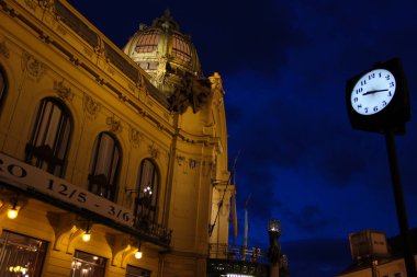Prag, Çek Cumhuriyeti - 16 Mayıs 2012: Belediye Binası (Obecni dum). Ön cephe, kubbe, balkon ve bayraklar bir sokak saatinin yanında alacakaranlıktaki mavi gökyüzüne karşı.