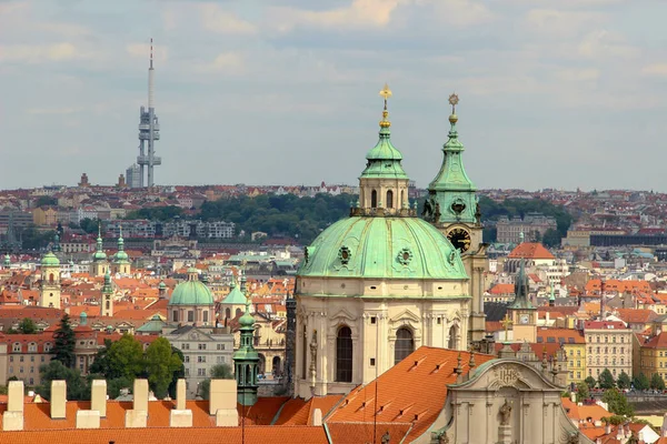 18. yüzyıldaki eski Barok St. Nicholas Kilisesi 'nin (Mala Strana) kulesi ve kulesi. Prag 'ın çatıları ve binaları. Televizyon kulesi olan bir siluet.