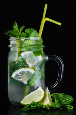Taze mojito kokteyli, limonlu, naneli ve buzlu koyu arkaplanda kavanoz bardaklı. Soğuk yaz içeceği ve kokteyl