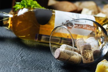 Taş bir masanın üzerindeki bardakta bir sürü şarap kapağı