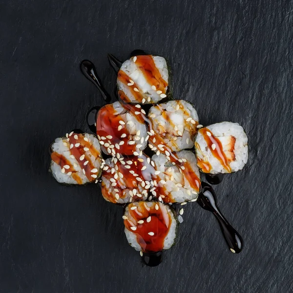 Karanlık bir arka planda geleneksel Japon yemekleri. Suşi, nigiri, çiğ somon bifteği, pilav, krem peynir, avokado, limon, zencefil turşusu. Asya yemekleri. Akşam yemeği partisi.