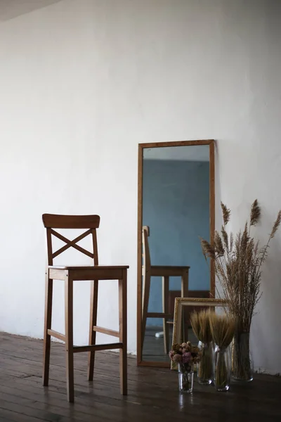 Composition: a chair, a mirror, dried flowers, wooden floor, light walls