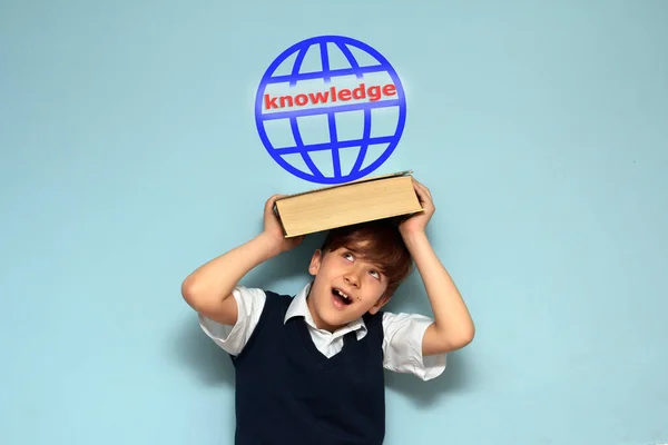 boy is pressed by a book on a book symbol of globe with the inscription knowledge.concept of studying