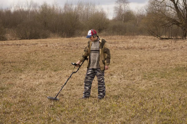 Metal dedektörlü bir adam eski tarlada bozuk para arıyor..