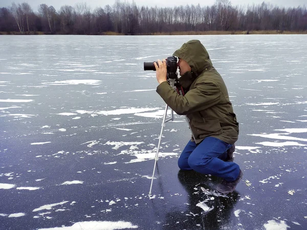 Fotoğrafçı objektife bakar. Buzun üzerinde. Kışın gölde.