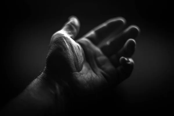 Black and white. Wrinkled left hand on a black background