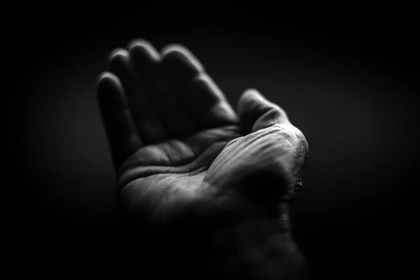 Black and white. Wrinkled right hand on a black background