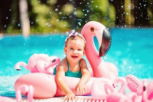 Smiling toddler girl swimming in the pool with pink flamingos Royalty Free Stock Images