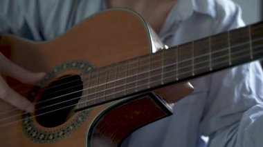 Genç bir kızın yatak odasında gitar çalarkenki görüntüsü..