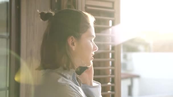 Κορίτσι Κλείνει Τηλέφωνο Στο Παράθυρο Του Δωματίου Της Ηλιοβασίλεμα Στο — Αρχείο Βίντεο