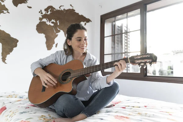 Çekici genç kız odasında gitar çalıyor..